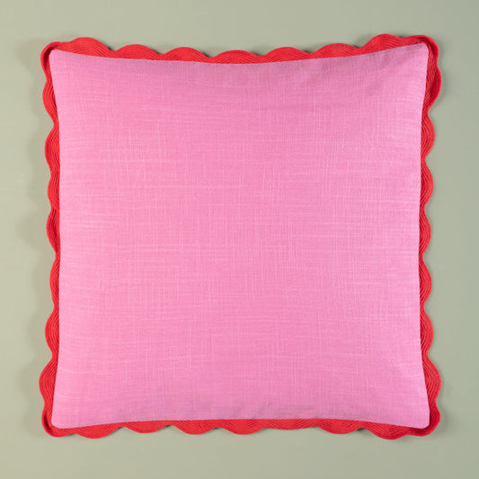 Pink pillow with red scalloped edge on a light gray background