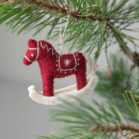 Red rocking horse handmade felt ornament hanging on a Christmas tree branch.