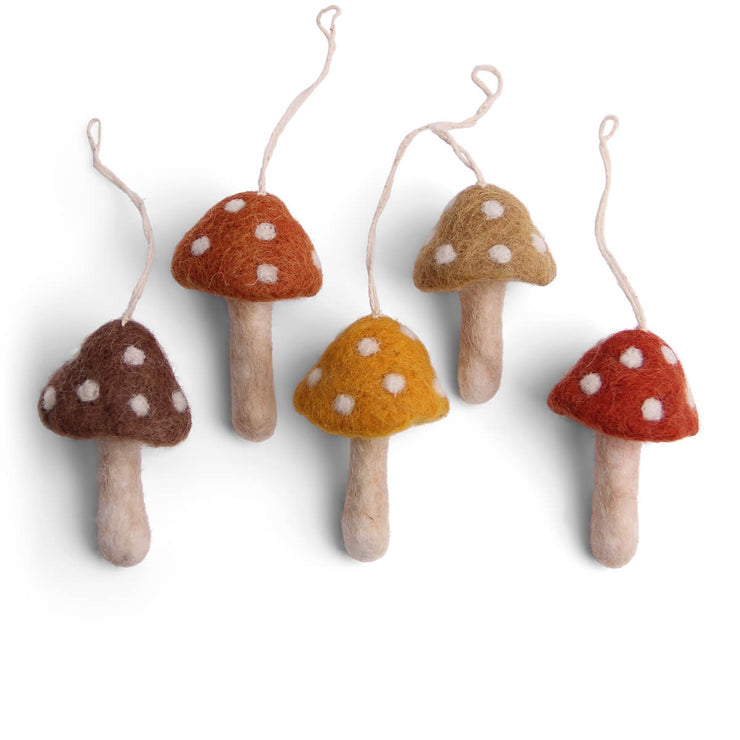 Five felt mushroom ornaments in assorted earthy colors with white polka dots and hanging twine, arranged on a plain white background.