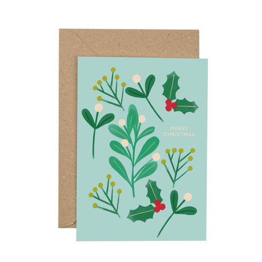Christmas card with holly and mistletoe design on a light blue background, featuring a brown envelope.