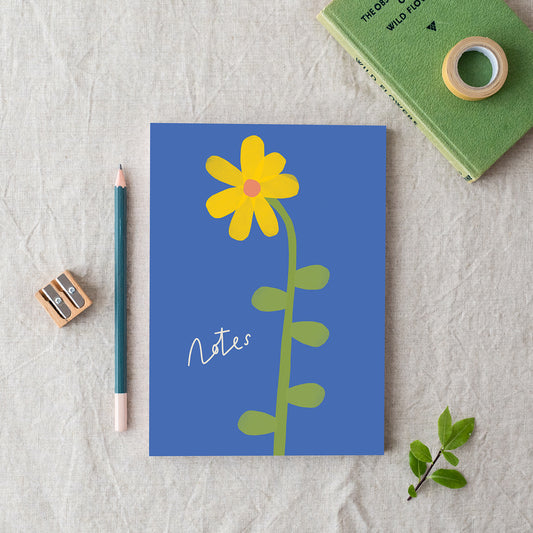A blue A5 notebook with a yellow daffodil illustration on the cover, made in Britain from bleed proof, eco-friendly, recycled paper with 100gsm inner pages.