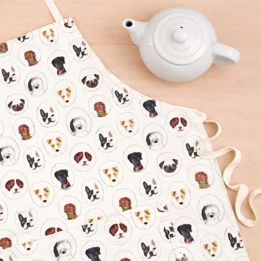 Tea towel with dog illustrations and a white teapot on a beige surface