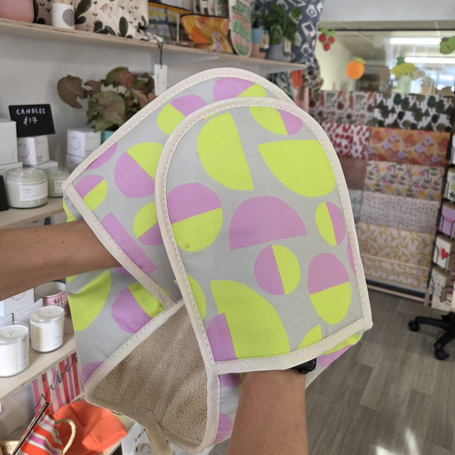 Pair of colorful oven mitts held in a store setting
