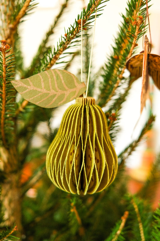 Decorative paper pear ornament hanging on a Christmas tree branch