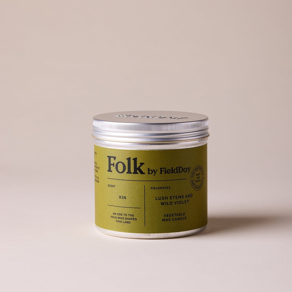Green candle tin with 'Folk' branding on a beige background