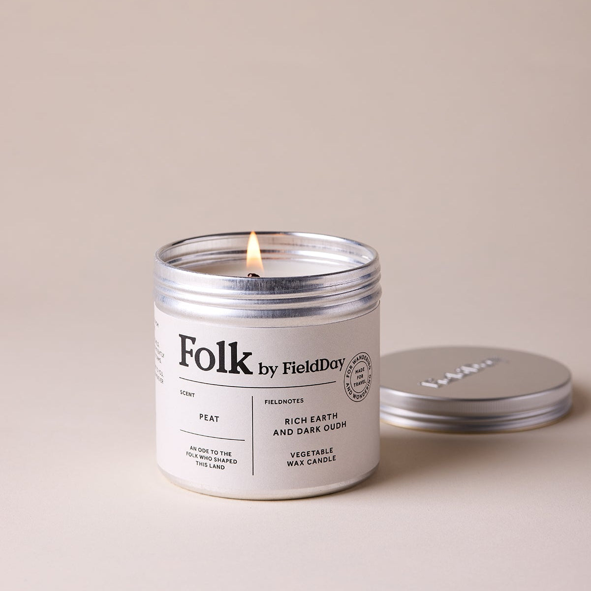 Candle labeled 'Folk by Field Day' with a lit wick on a beige background