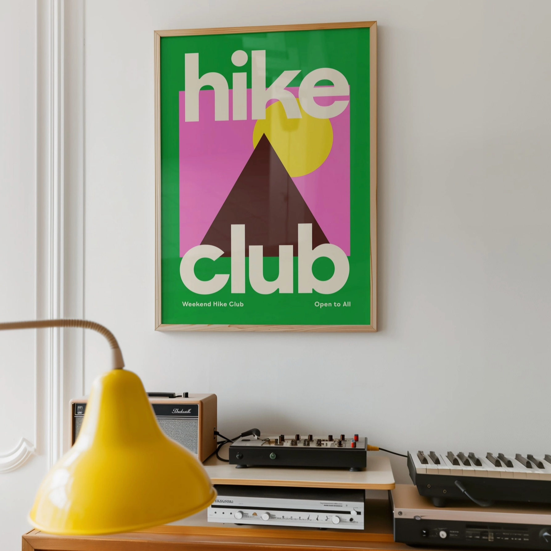 Framed poster with 'hike club' design on a wall above vintage electronic equipment.