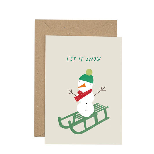 Greeting card with a snowman on a sled and 'Let it Snow' text, featuring a brown envelope.