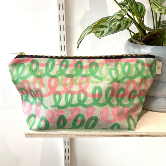 A multicolored cosmetic bag with a pink and green loop pattern Printed on sustainable cotton, with a high quality YKK brass zip and natural panama cotton lining.