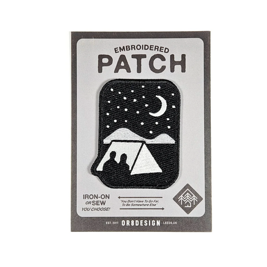 Embroidered patch with a design of two people under a tent at night, on a white background.