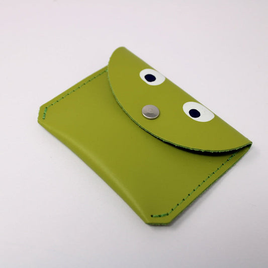 Green leather coin purse with eye designs on a white background