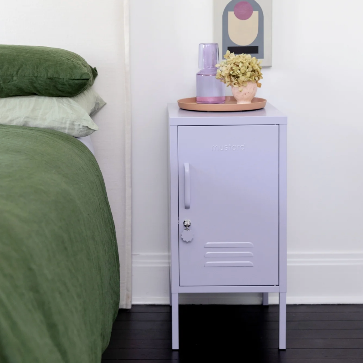Bedroom with a green bed and a purple mustard made locker with decorative items.