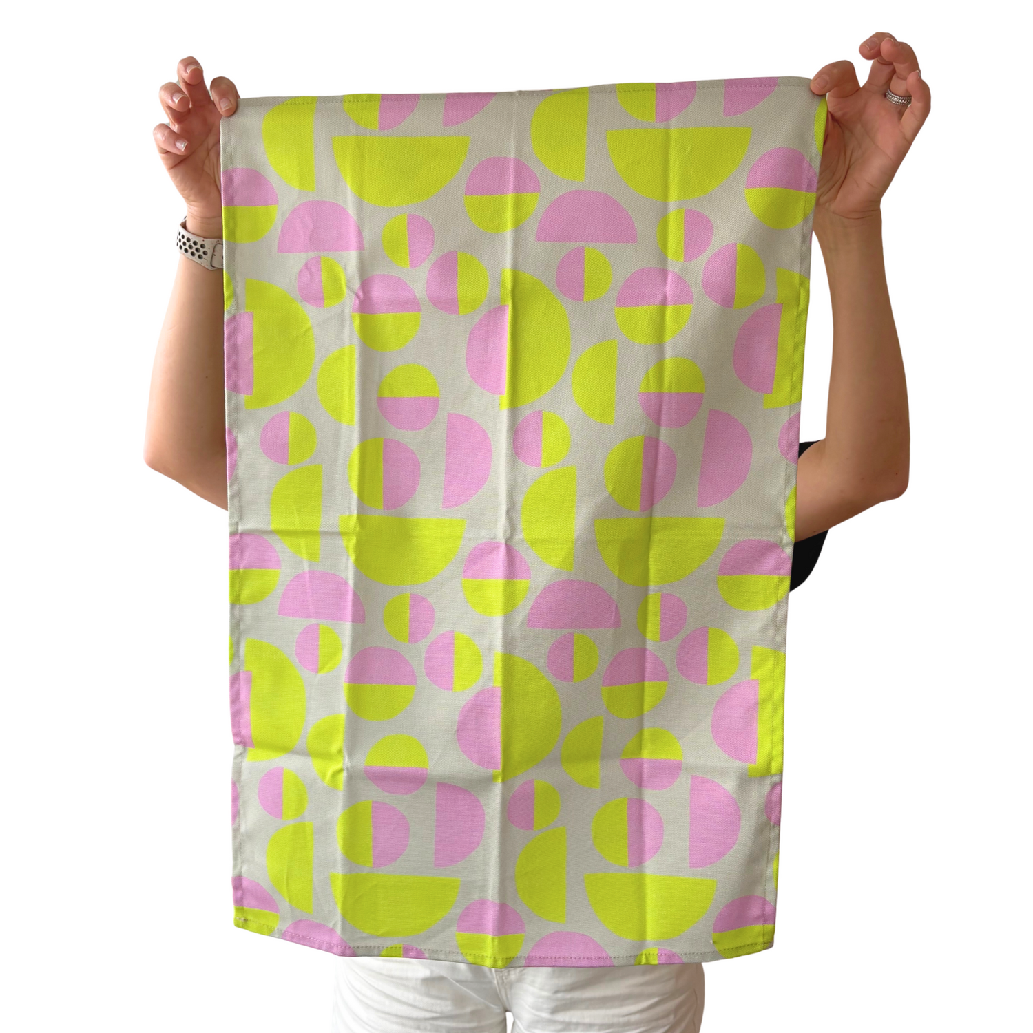 Person holding a colorful patterned towel with pink and green shapes on a white background