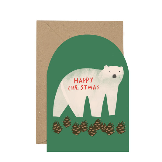 A Christmas greeting card with a kraft envelope, featuring an illustration of a white polar bear on a muted green background with the words 'HAPPY CHRISTMAS' in red and pinecones along the bottom.