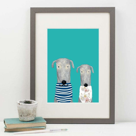 Framed artwork of two dogs on a teal background, displayed on a white surface