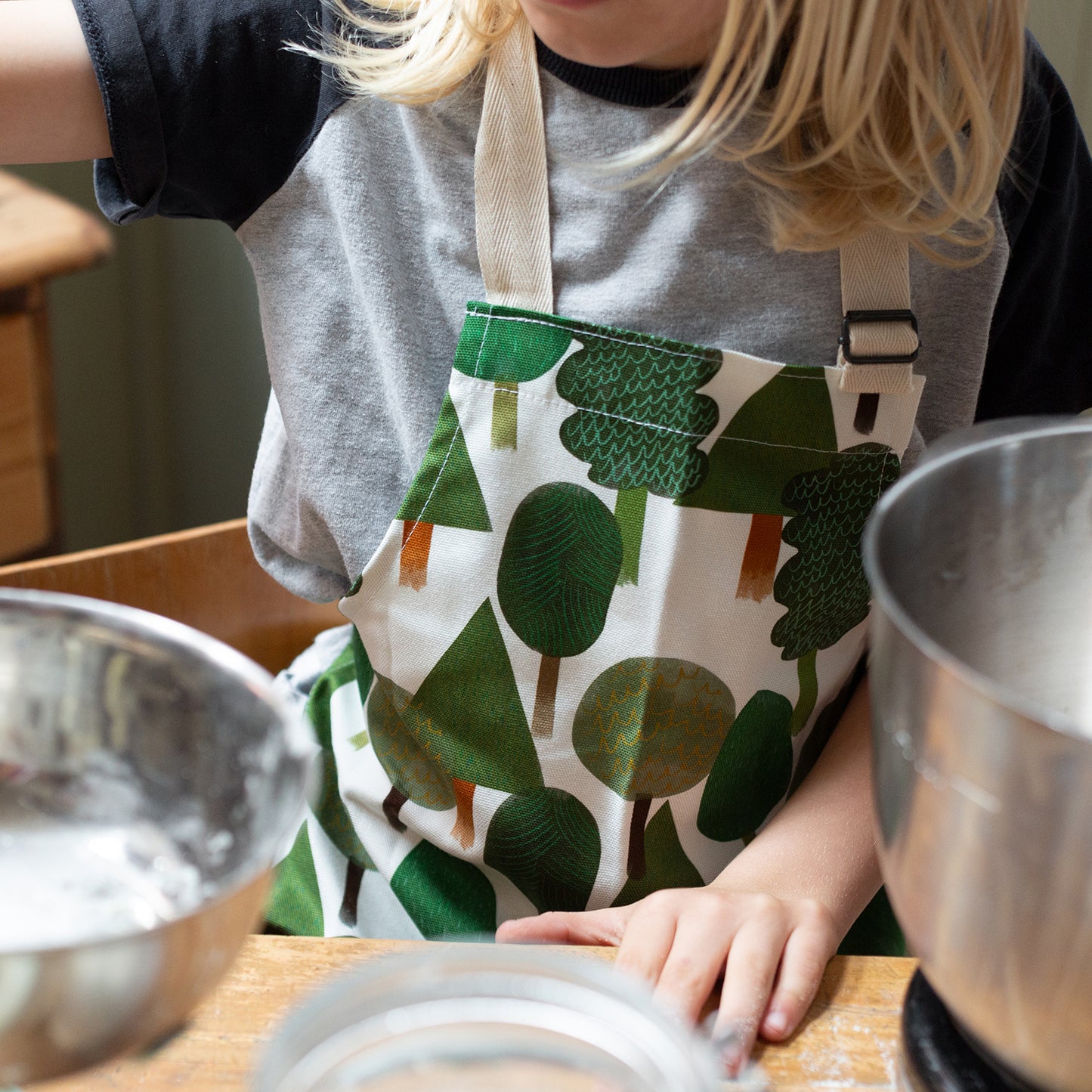 outdoor inspired childrens apron with trees of various shades of green on a white background