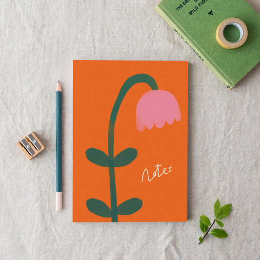 An A5 floral notebook with an orange cover featuring a pink tulip illustration, titled 'Notes'. made in Britain from bleed proof, eco-friendly, recycled paper with 100gsm inner pages.