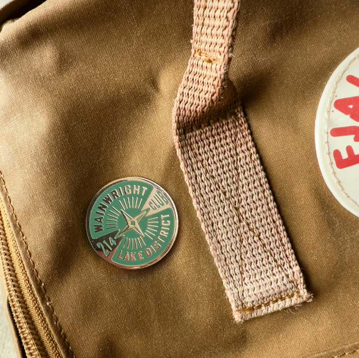 Close-up of a brown bag with a green and white wainwright pin badge