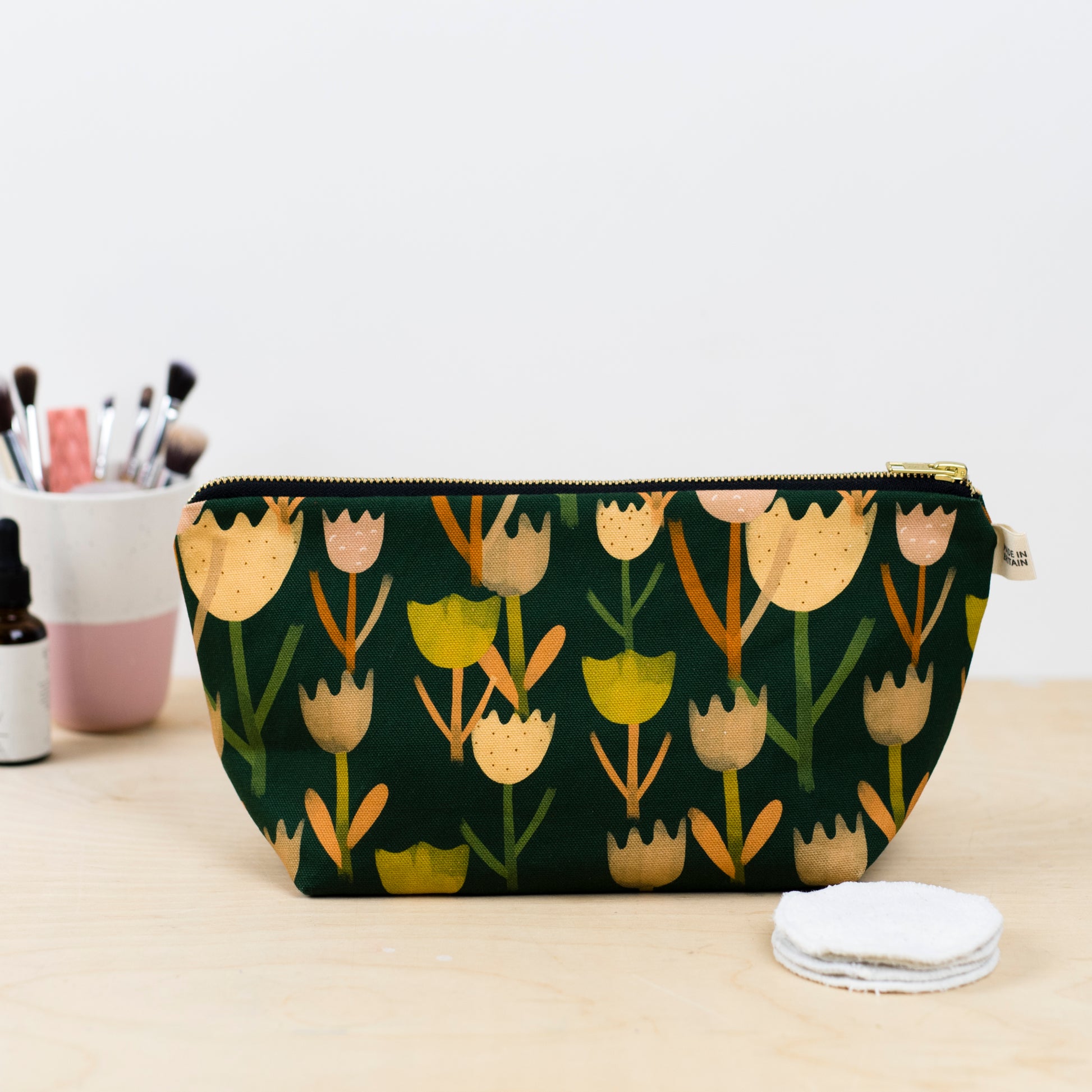 A green wash bag with a multicolor tulip pattern, Printed on sustainable cotton, with a high quality YKK brass zip and natural panama cotton lining.