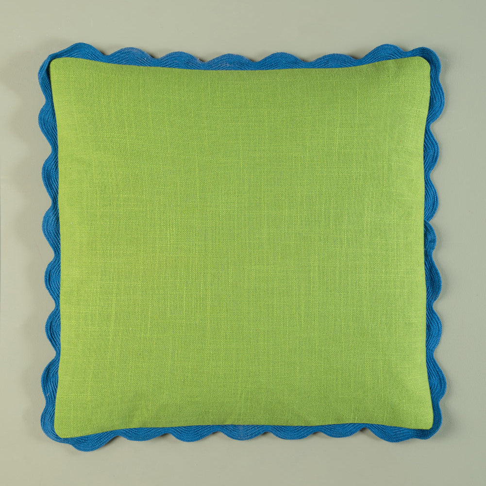 Green pillow with blue scalloped edge on a beige background