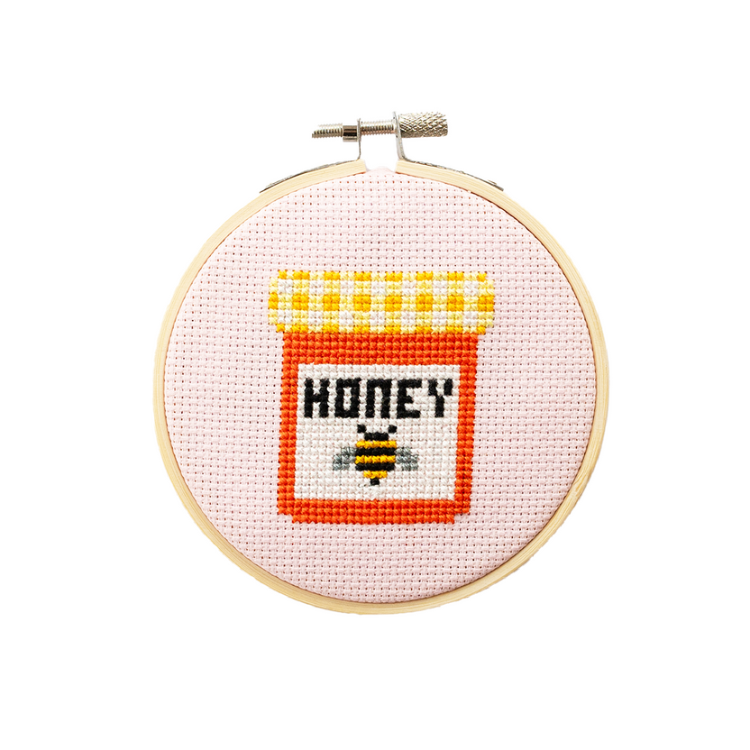 Cotton clara honey cross stitch kit. shows finished design in wooden embroidery hoop