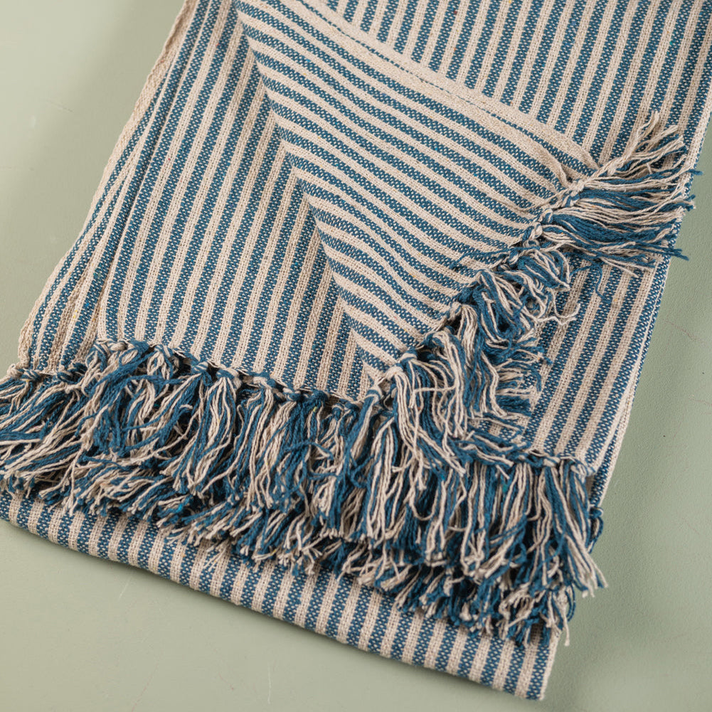Blue and white striped blanket with fringes on a light green background