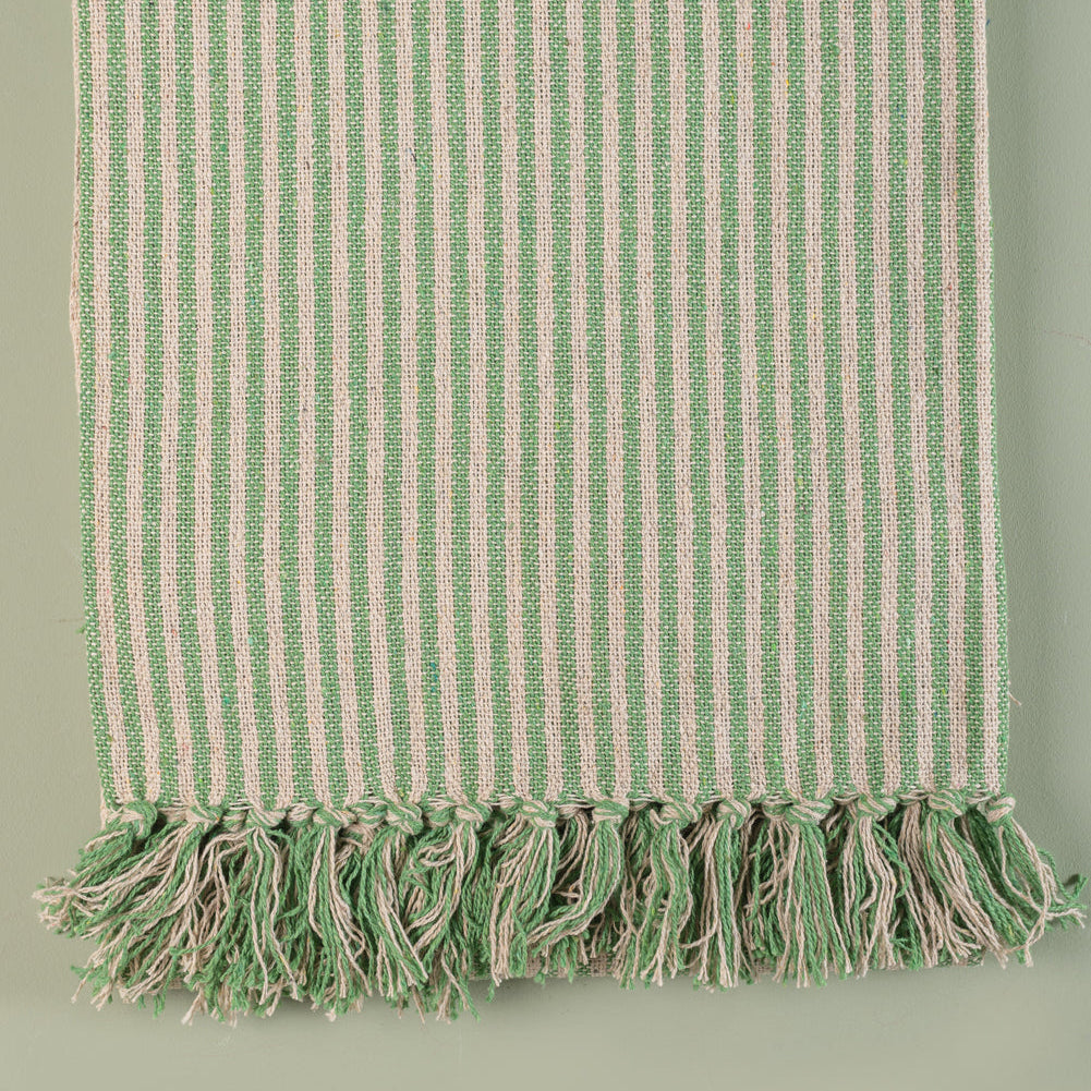 Green and white striped towel with tassels on a light green background