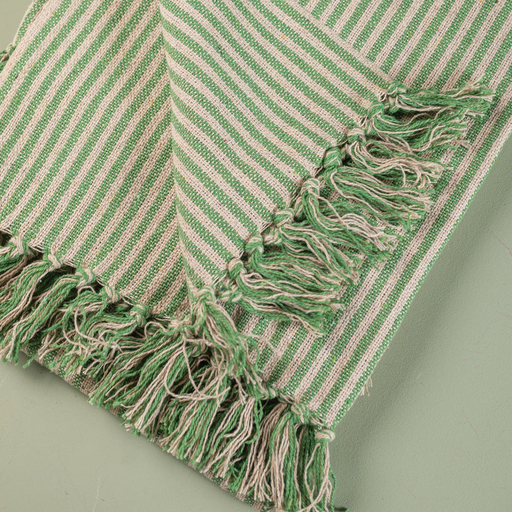 Green and beige striped towel with tassels on a light green background