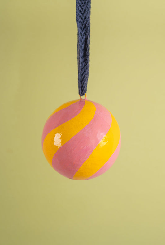 Decorative bauble with pink and yellow stripes hanging on a string 