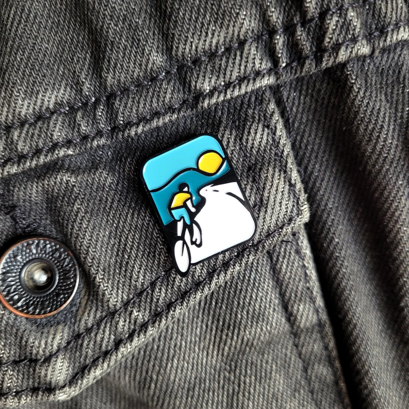 Pin with a design of a cyclist on denim fabric