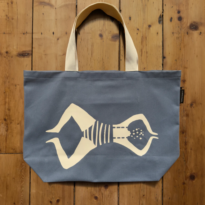 Blue tote bag with a white graphic of a person on a wooden surface