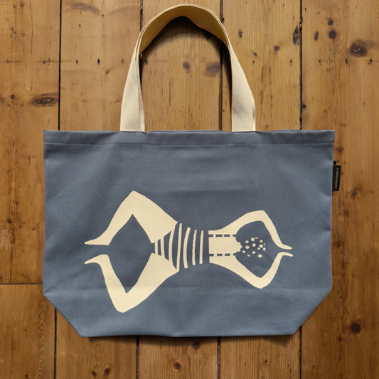 Blue tote bag with a white graphic of a person on a wooden surface