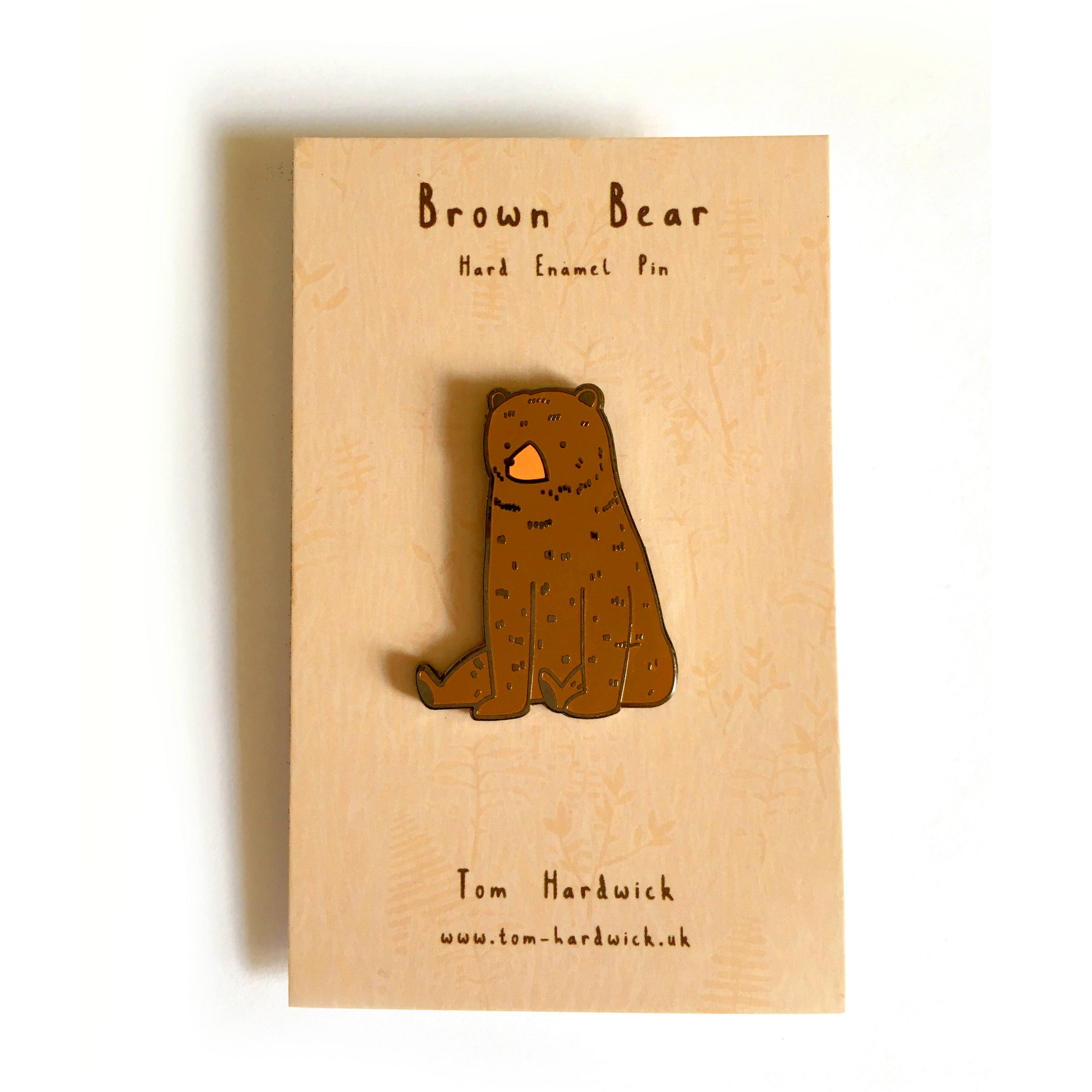 Brown bear hard enamel pin on a wooden card with branding information.