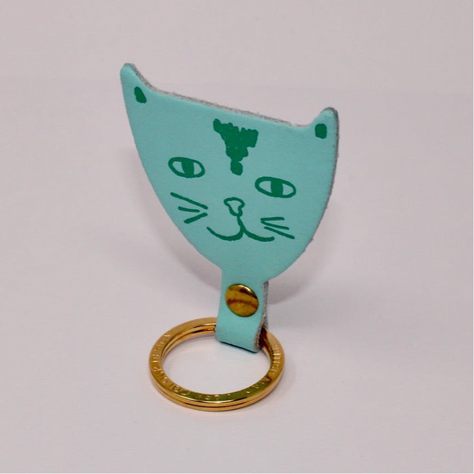 Cat-shaped keychain with gold ring on a light gray background