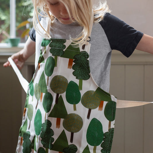 Kids apron with various trees on and an adjustable neck strap. made in Britain