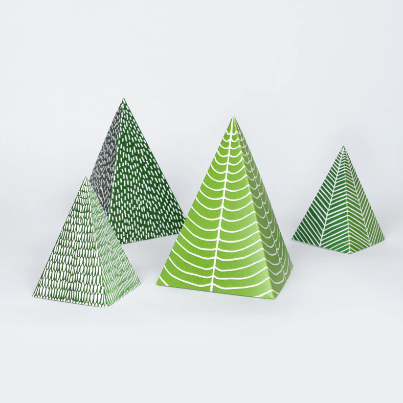 Four green triangular paper trees with patterned designs on a white background