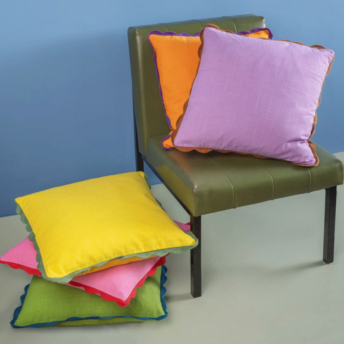 a green leather chair with a range of colourful cushions