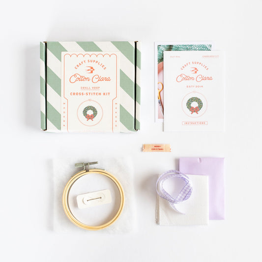 Cross-stitch kit with hoop, thread, and pattern on a white background