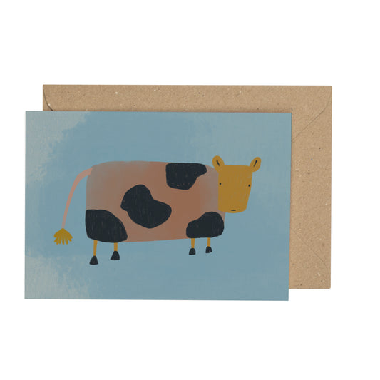 a tiny card with an illustration of a cow on a blue background with a brown envelope