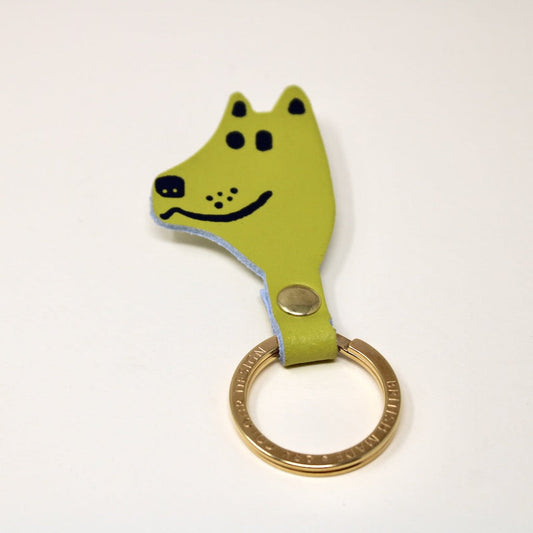 Green dog-shaped keychain with a gold ring on a white background