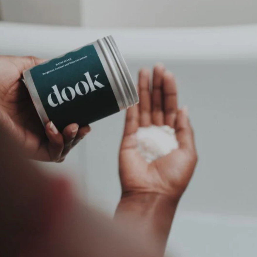 Person holding a container of 'dook' product with a blurred background