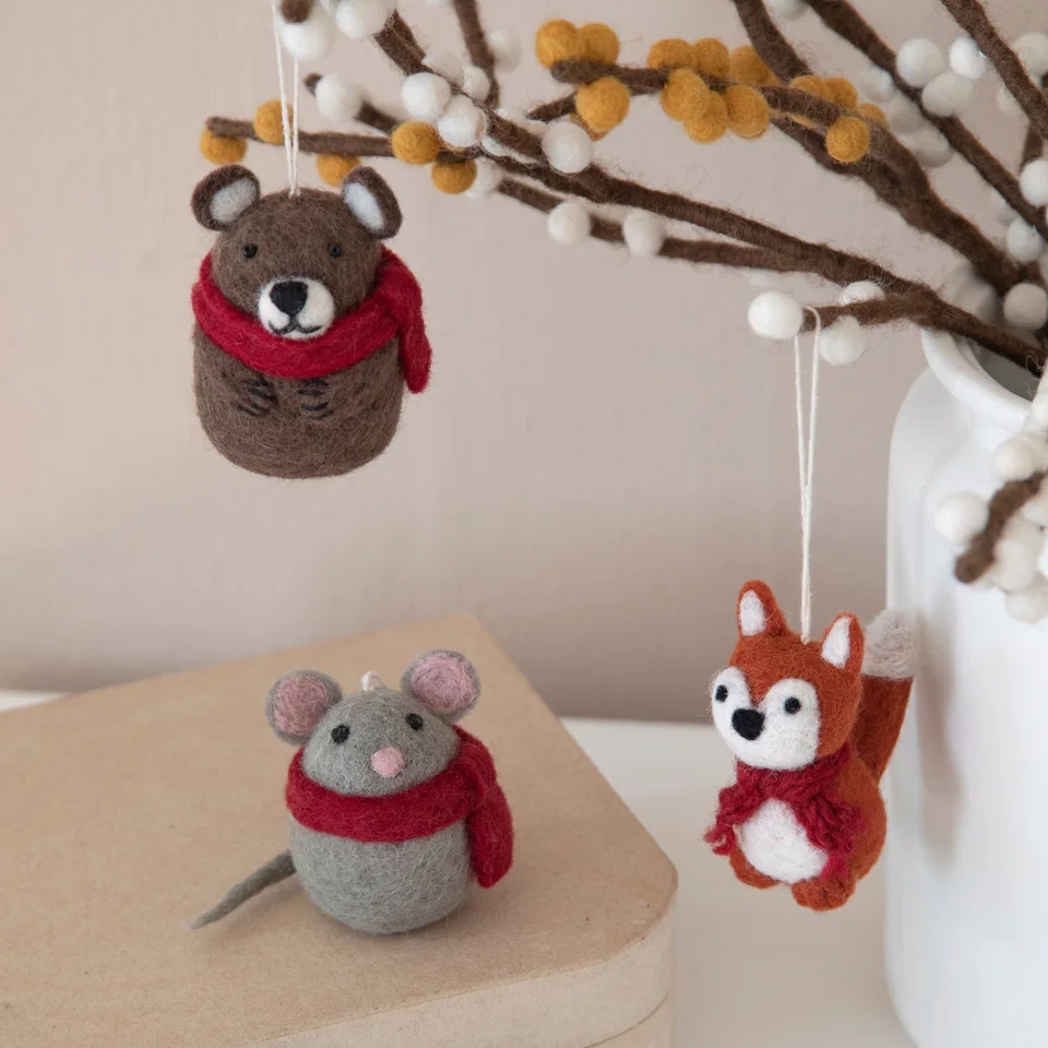 Three felt animal ornaments hanging from branches in a white vase, alongside a small gray mouse ornament resting on a beige box. The ornaments include a brown mouse with a red scarf, a gray mouse with a red scarf, and an orange-brown fox with a red scarf.