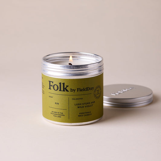 Candle with a green label and silver lid on a beige background