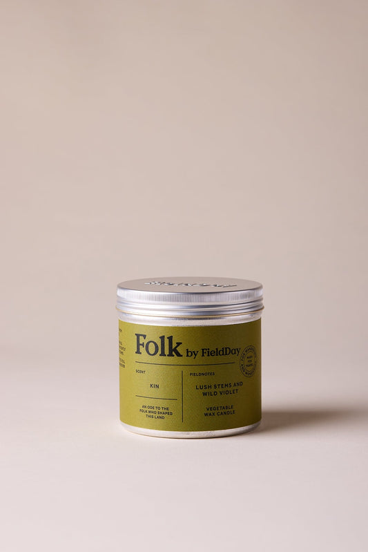 Green candle tin with 'Folk' branding on a beige background