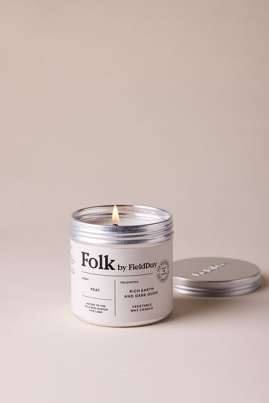 Candle labeled 'Folk by Field Day' with a lit wick on a beige background