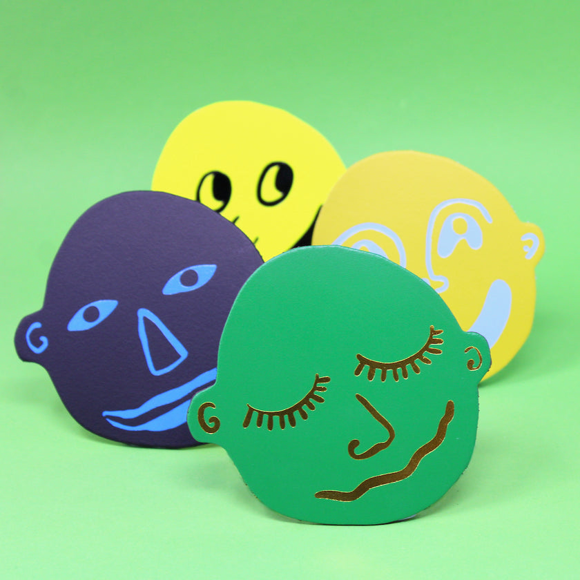 Four colorful face-shaped leather coasters 