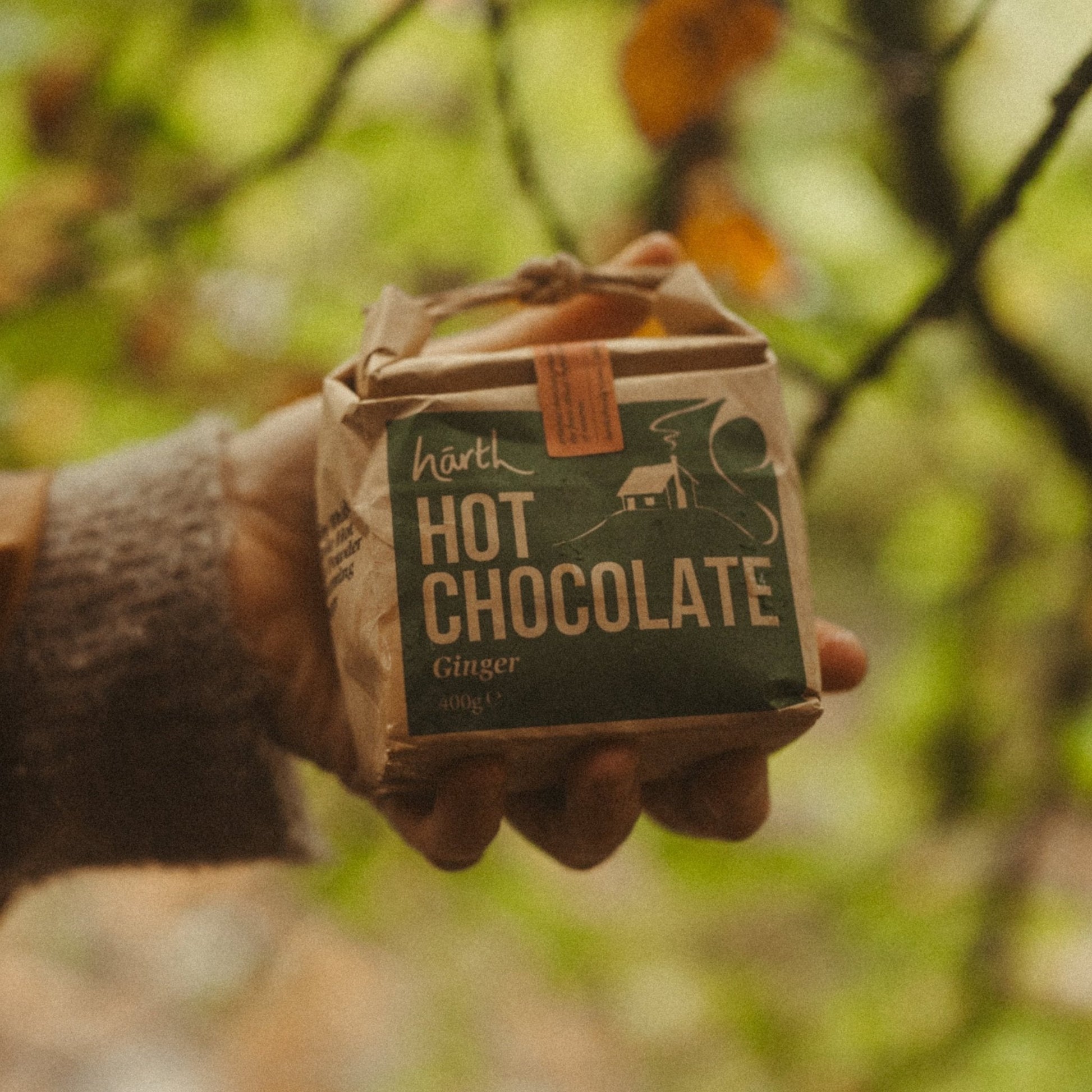 Hand holding a box of Harth hot chocolate against a blurred natural background