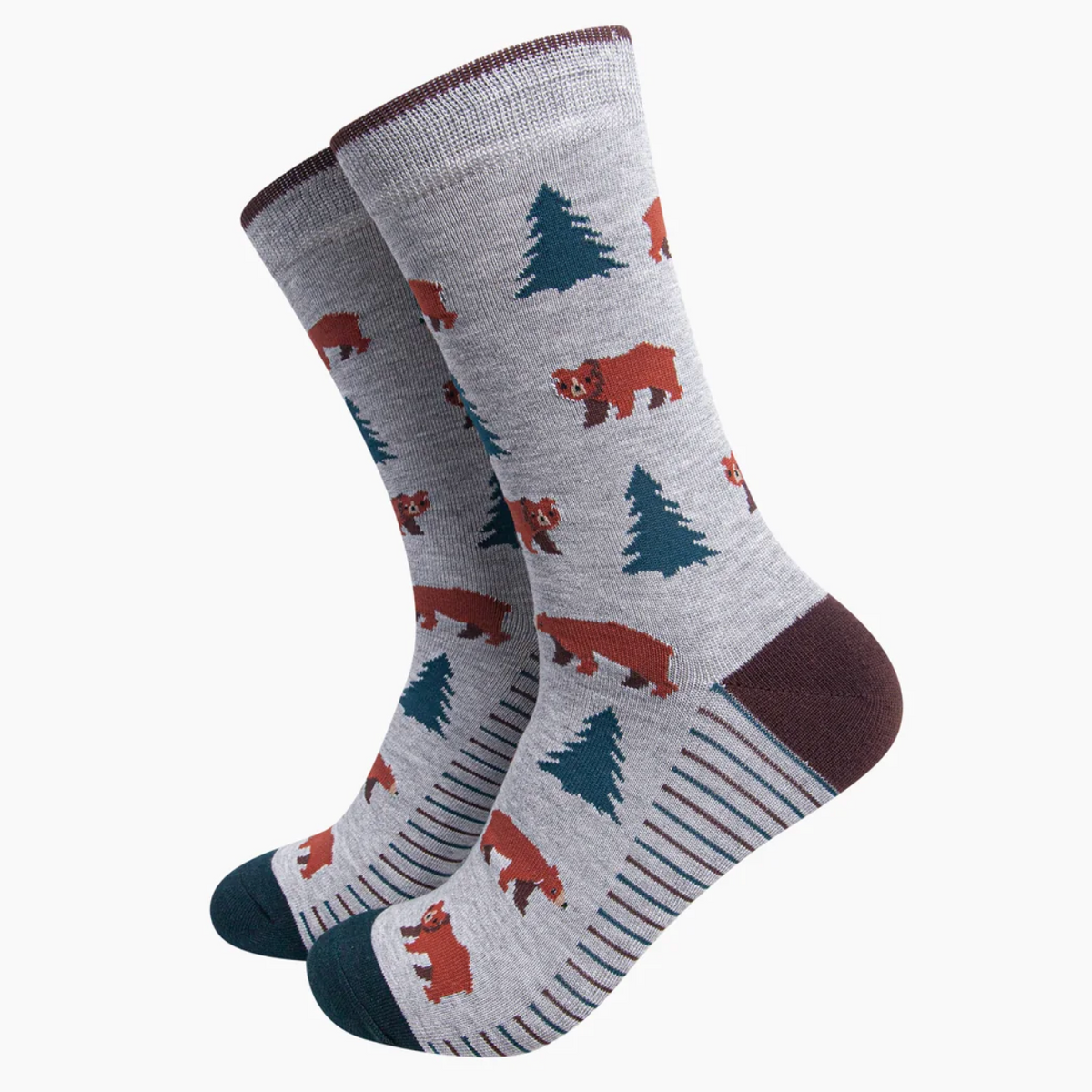 A pair of crew socks with a heather gray base featuring a pattern of brown bears, dark green pine trees, and dark teal toes and heels, with thin blue and white stripes on the sides.