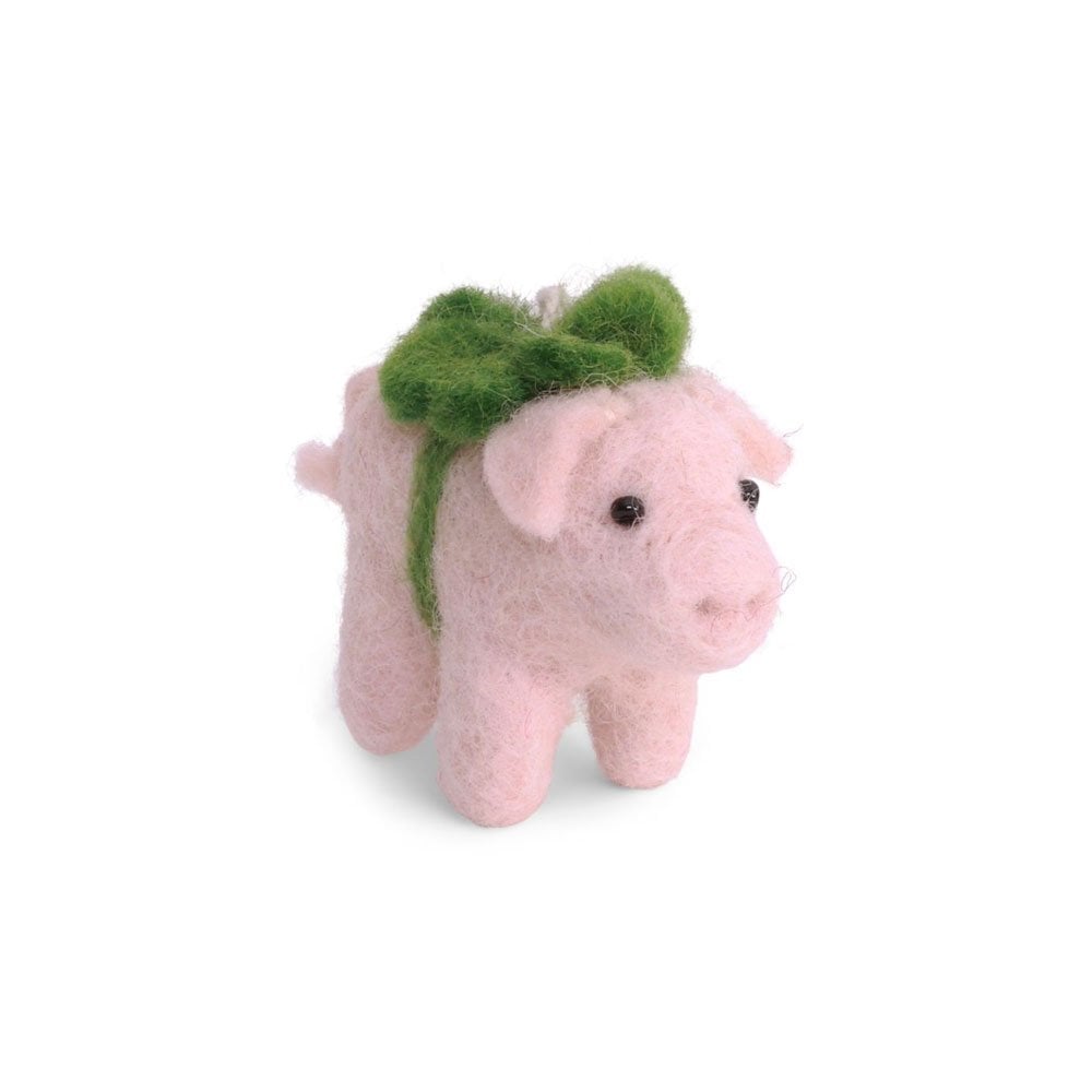 A pink felted wool pig decoration with a green clover around body standing on a white background.