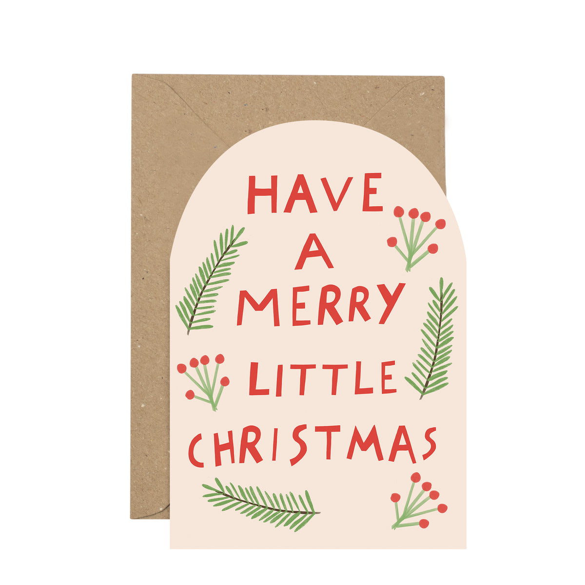 A Christmas greeting card with an arched cream front featuring the phrase “HAVE A MERRY LITTLE CHRISTMAS” in red lettering, decorated with green pine branches and red berry illustrations, shown with a brown kraft envelope behind it on a white background.